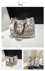 Detail of graffiti tote bag featuring brown handles, silver chain, and plush pendant