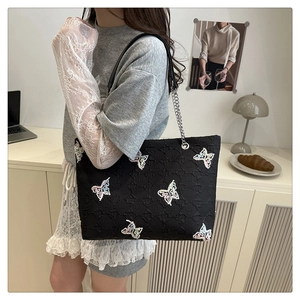 Detail of black tote bag with embroidered butterflies and chain leather shoulder strap