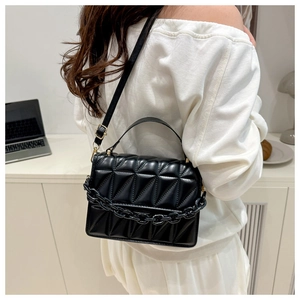 Détail du sac matelassé noir avec chaîne épaisse et bandoulière réglable en cuir