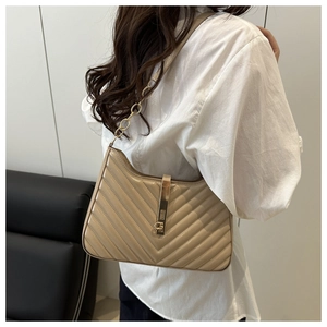 Close-up of beige quilted shoulder bag with V-shaped stitching and gold chain strap