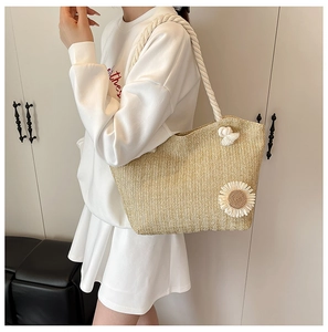 Detail of straw tote bag featuring white sun flower decoration and woven texture