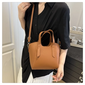 Brown lychee leather handbag detail with adjustable strap and golden hardware accents