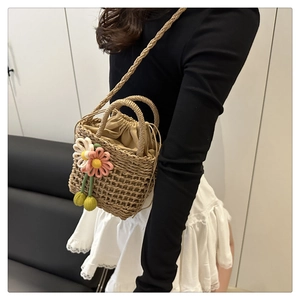 Detail of hand-woven straw bag featuring decorative floral accents and drawstring lining