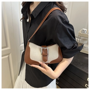 Close-up of crescent hobo bag with ivory canvas, brown leather trim and silver buckle