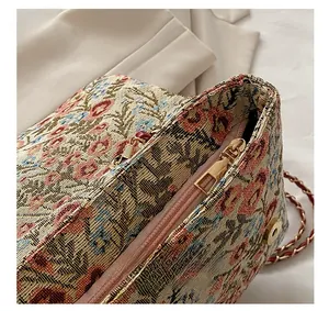 Detailed close-up of floral jacquard envelope bag with golden zipper and woven chain strap