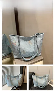 Detailed close-up of light blue quilted tote bag featuring colorful 3D butterfly embroidery