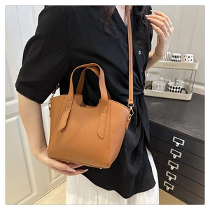Macro shot of brown textured leather small trapezoid tote with metallic buckle details