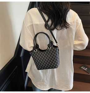 Détail du mini sac seau vintage avec poignée en cuir noir et finitions dorées