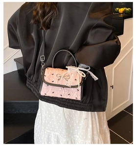 Detail view of pink bow-knot handbag with lace pearl charm and silver metal clasp