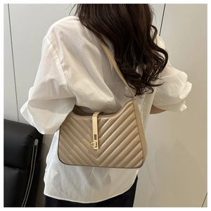 Detail of khaki quilted shoulder bag with glossy finish and gold vertical metal clasp
