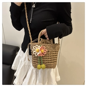 Detail view of handmade straw bag with 3D floral decorations and drawstring closure
