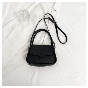 Close-up of black lychee grain texture and circular buckle on a small square handbag
