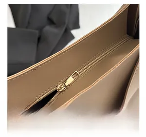 Close-up of golden metal zipper and smooth brown leather stitching on a tote bag