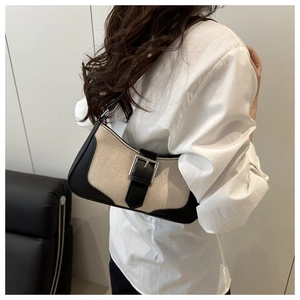 Chic beige linen and black leather shoulder bag with a silver buckle worn by a model
