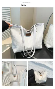 Detail view of large white woven tote bag featuring brown leather patch and metal rivets
