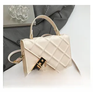 Detail of cream quilted handbag with elegant gold and black twist-lock and chain handle