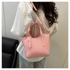 Side view of pink textured leather tote bag with round handles and adjustable shoulder strap