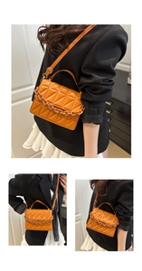 Detail of orange quilted crossbody bag with thick chain handle and gold-tone hardware