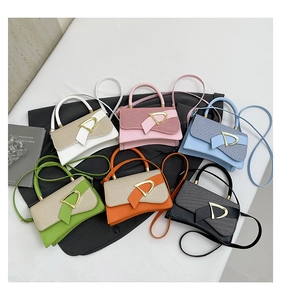 Flat lay of small crossbody bags in six vibrant colors with gold D-buckle detail