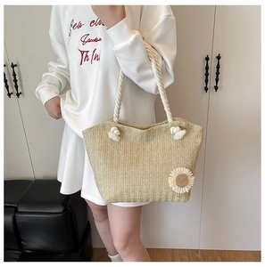 Detail of woven straw tote bag with 3D daisy decor and white rope handles
