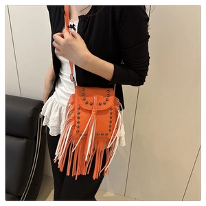 Close-up of orange crossbody bag featuring retro metal studs and long fringe details