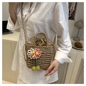 Detail of hand-woven straw bag with floral knit accents and brown drawstring closure