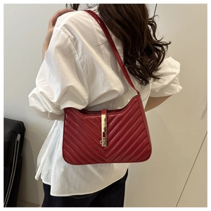 Detail of red quilted shoulder bag with V-pattern stitching and gold vertical lock