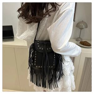 Detalle de bolso bandolera negro con flecos y remaches vintage en piel granulada