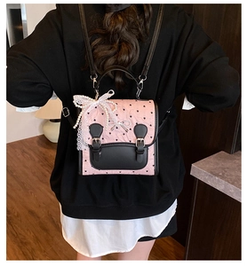 Détail du sac à dos en cuir rose et noir avec motifs de cœurs et ornements de perles