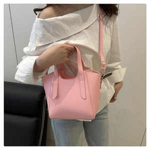 Detail view of pink lychee leather handbag showing handle and adjustable strap stitching