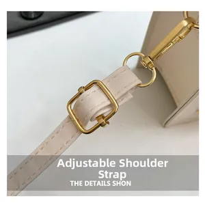 Detail view of adjustable cream faux leather shoulder strap with gold metal buckle