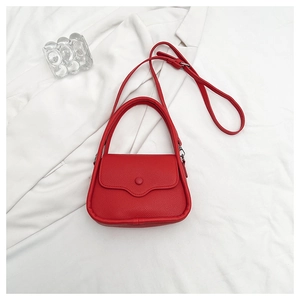 Top view of red lychee pattern leather handbag with adjustable strap on white fabric