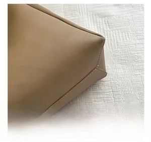 Detail view of precise double-stitched seams on tan leather tote bag corner