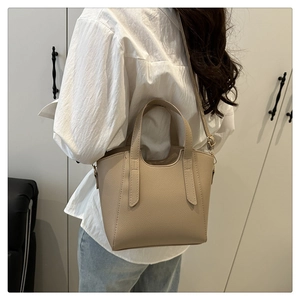 Litchi texture leather bucket bag shown being worn with adjustable shoulder strap