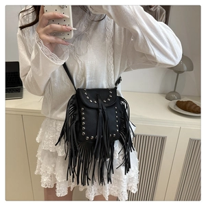 Detail of black crossbody bag with silver studs and long tassels on a stylish strap