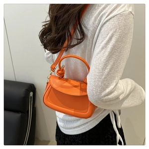 Detail of orange crossbody bag featuring a unique knotted handle and adjustable strap