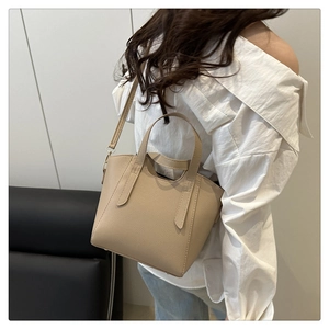 Chic beige lychee grain bucket bag shown as a shoulder bag on a model from a side view