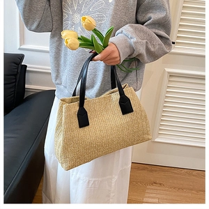 Hand-held straw woven basket bag with stylish black handles for casual spring look