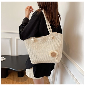 Detail of beige straw tote bag featuring V-shaped texture, daisy decor and cotton rope handle