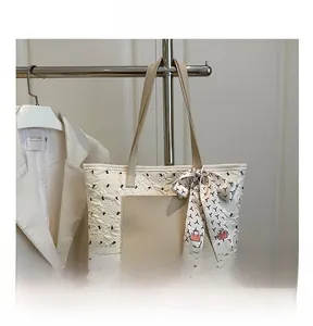 Détail d'un sac cabas blanc matelassé avec poche en cuir beige et foulard décoratif nœud