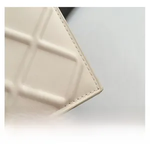 Close-up of cream quilted faux leather texture with fine stitching on a small square bag