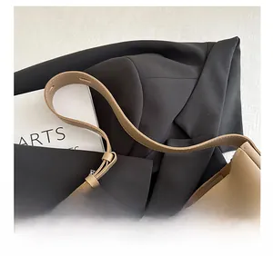 Detail of khaki tote bag wide shoulder strap and smooth leather finish on black blazer