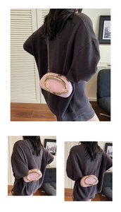 Detail view of pink oval evening bag with large gold metal handle and chain strap