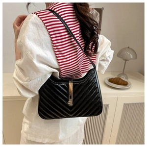 Close-up of black quilted shoulder bag with gold metal clasp and elegant V-stitching