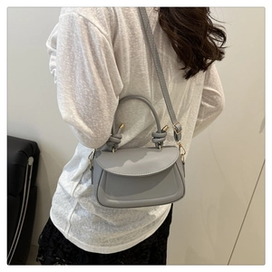 Rear view of a model wearing a grey crossbody bag with knotted handle detail