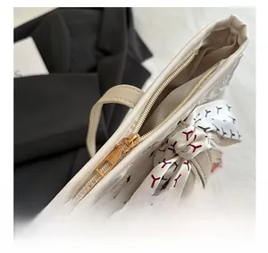 Détail de la fermeture éclair dorée et du foulard en soie imprimé sur un sac à main blanc