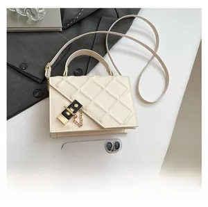 Close-up of cream quilted shoulder bag with gold metal lock and chain hardware detail