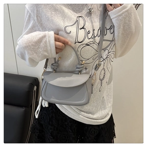 Detail of light gray synthetic leather handbag with gold hardware and shoulder strap