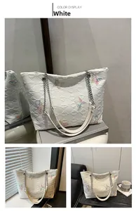 Detailed view of white quilted tote bag with colorful butterfly embroidery and chain strap