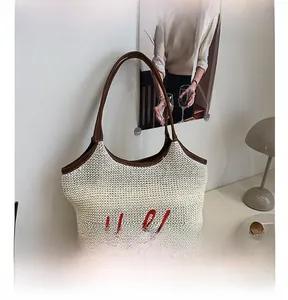 Close-up of beige woven tote bag with red Hello embroidery and brown leather handles